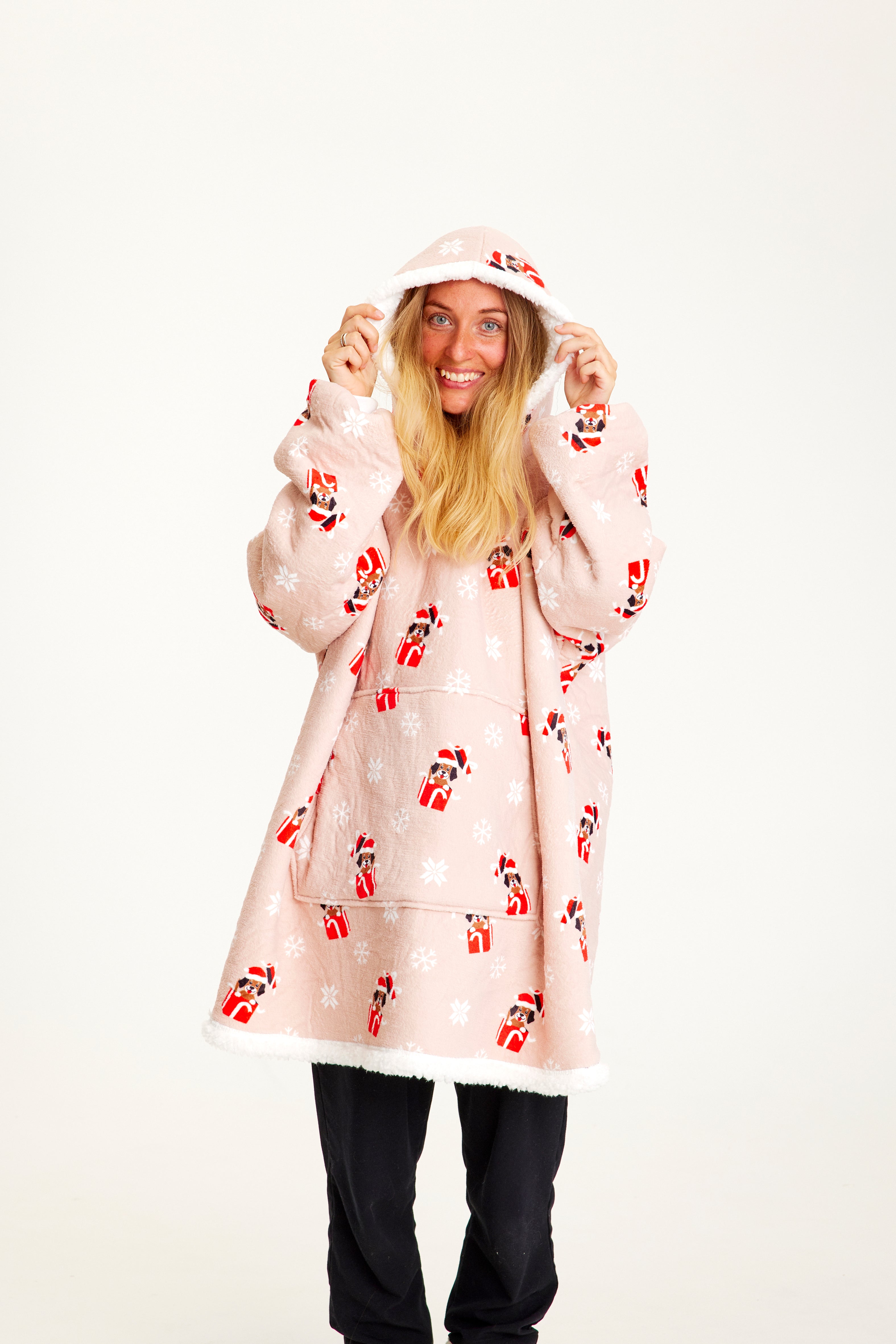 Una donna che indossa una felpa rosa con cappuccio natalizio con sopra dei cani.